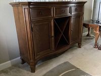 Front view of antique style wooden hutch with three drawers, two side cabinet doors, and an X-shaped central wine rack.
