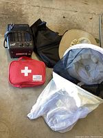 Photo of all items: one black Comfort Zone ceramic portable heater, black bag, red Walgreens first aid med kit, bee keeper hat with mesh net, beige yard hat.