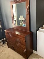 Wood dresser with carved leaf designs and attached large mirror reflecting room interior
