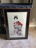 Framed Japanese art print featuring a woman in a red kimono depicted in traditional style art, signed by artist Otsuka. The artwork is approximately 25x36.5 inches and is matted and framed in wood.