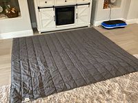 Full view of the gray weighted blanket laid flat on the floor showing size and color.