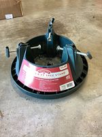 Black plastic Christmas tree stand with label indicating it supports 8 ft tall trees and up to 80 lbs.