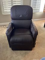 Front view of brown faux leather lift chair showing the seat, backrest, and padded armrests. Includes visible side control panel for lift function.