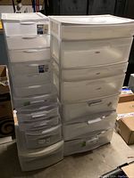 Multiple plastic garage storage cabinets including tall and medium units with multiple drawers, various sizes and translucent white plastic construction.