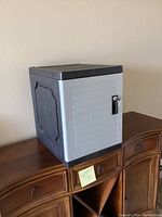 Large plastic lockbox with gray ribbed front panel, dark gray sides and top, placed on wooden furniture.