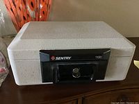 Front view of Sentry Safe 1100 portable fireproof lockbox with key in lock.
