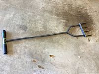 Full view of the handheld Yard Butler soil aerator showing the handle and three metal tines in black coating.