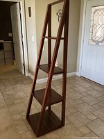 Full view of the wooden ladder shelf showing the tiered design and condition.
