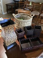 Wicker basket with items inside, leopard print umbrella holder standing beside it, and four dark brown utensil or napkin holders in front on a table.