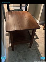 Top and angled view of wooden all purpose table showing the wood plank top, tapered legs and lower shelf.