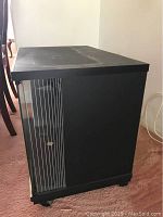 Side view of the black rectangular TV cabinet showing the plain black side panel and glass door with vertical lines.