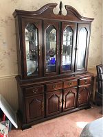 Front view of dark cherry wood solid China cabinet with four glass doors on upper section and four lower wood doors with brass handles and drawers