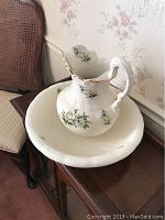 Pitcher placed inside basin showing floral pattern and gold trim details