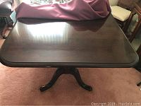 Full top view of the wooden dining table showing a dark polished surface with rounded corners.