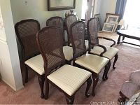 Six caneback dining chairs arranged in two rows on carpeted floor