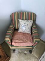 Vintage childrens fabric chair with multicolored vertical stripes, pink removable cushion, and floral pillow sitting in corner.
