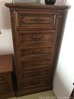 Photo of entire chest of drawers showing six drawers with metal pulls and wood decorative paneling.