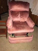 Front view of a pink upholstered recliner chair with a footrest extended.