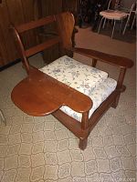 Front angle photo of wooden chair showcasing drop leaf shelf on right armrest and floral cushions on seat and backrest.