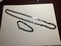 Photo showing full length of the gold plated chain and matching bracelet laid flat on white surface.