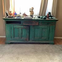 Full front view of sideboard showing green paint, doors, cubbies, and drawers.