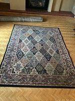 Full view of Art Deco style carpet displayed on hardwood floor showing overall pattern and size, with fireplace in background.