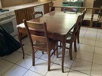 Wooden kitchen table with five chairs around it showing overall structure and setting.