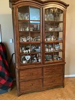 Full frontal view of the tall wooden china cabinet showing two glass-paned doors and four drawers below