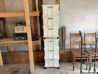 Stacked view of six white plastic storage containers, showing two containers with wheels at base and four standard containers stacked above, highlighting stackable design and handles.