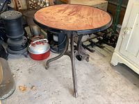 Full view of the round table showing marble top with reddish cream swirls and black metal rim, standing on cast iron legs.
