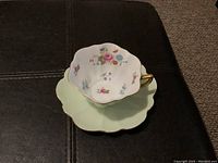 Top view of Shelley cup placed on matching scalloped saucer showing floral interior design and gold trim