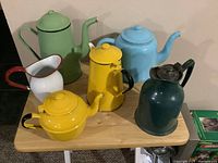 Overview shot of all six pieces showing colors, sizes, and handles reflecting enamel and metal materials