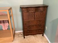 Front view of solid oak dresser with four drawers and two cupboard doors, showing wood grain and brass handles.