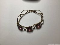 Top view of the entire bracelet showing gold-tone metal links and three prominent purple stones.