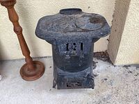 Front view of vintage Dominion pot belly stove showing top cooking surface, front door with venting mechanism, and cylindrical body shape.