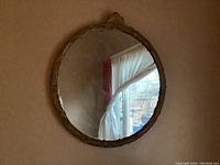 Front view of the vintage round wall mirror showing full reflective surface and ornate frame