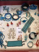 Overview of blue jewelry lot showing multiple items including bead bracelets, fishbone silver earrings, turquoise cuffs, coral bead earrings and butterfly motif earrings.