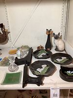 Overview of lot showing four octagonal plates, wooden cat sculpture, ceramic cat figurine, crystal perfume bottle, crystal squirrel, and plate stands