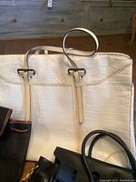 Close-up of large white Italian leather bag with crocodile pattern and two handles