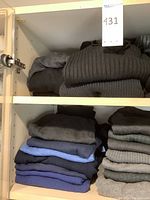 Two shelves with folded men's sweaters, showing dark and neutral colors