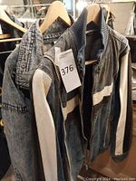 Two denim jackets hanging on wooden hangers against a mirror