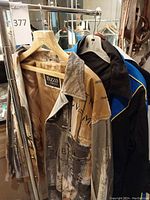 Three jackets on rack: leather graffiti jacket in front, black and white bomber at center, blue and black zip-jacket in back
