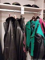 Four jackets on hanger rod with two black bomber jackets and two colored Jeff Hamilton jackets visible