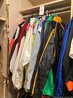 Rack of approximately 11 assorted men's windbreaker jackets on hangers, various colors