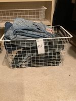 White wire basket filled with folded men’s jeans in various denim colors