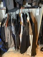 Multiple outerwear pieces and jeans hanging on rack
