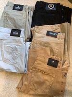 Five folded Versace pants in neutral tones