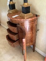 Front view of demi-lune side table showing marble top and open cabinet door with three drawers