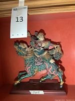 Front view of full statue against red background with lot tag visible