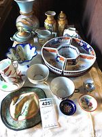 The lot of Asian porcelain items including vases, teapot, sugar creamer, Lazy Susan tray, cups, and a decorative fabric piece.